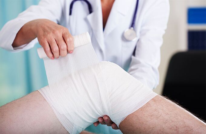doctor bandaging the knee joint with arthrosis